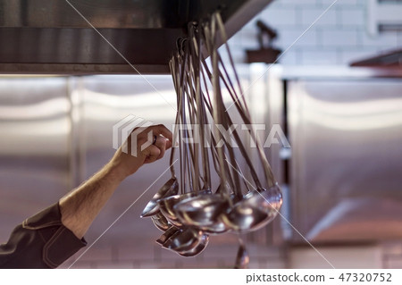 Male hands choosing a metal ladle. Preparation of food concept 47320752