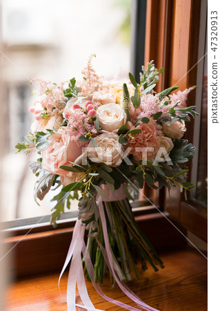 pink and peach wedding bouquet stands on the windowsill 47320913