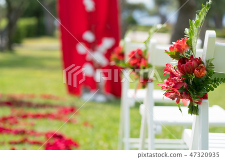 chairs decorated with fresh flowers in red tones for the wedding ceremony on the green lawn chairs decorated with fresh flowers in red tones for the wedding ceremony on the green lawn 47320935