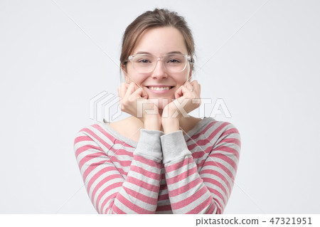 Young woman holding her fists to her chin in an expression of excitement 47321951