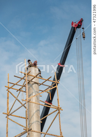 Workers sitting on the top of column at site 47321996