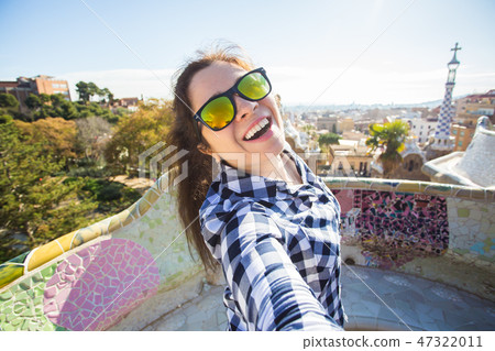 Travel and holidays concept - Beautiful young woman looking at camera taking photo with smart phone 47322011