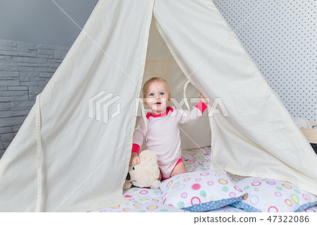 Child playing with a teepee tent Child playing with a teepee tent 47322086
