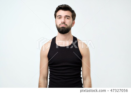 Unsatisfied sleepy guy with messy hair standing over gray background. 47327056