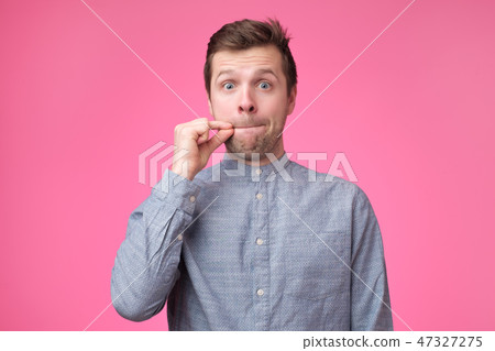 Young man showing a sign of closing mouth and silence gestur 47327275
