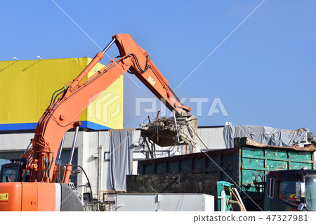 拆除工作期間,液壓挖土機將工業廢棄物裝入自卸卡車 拆除工作期間,液壓挖土機將工業廢棄物裝入自卸卡車 47327981