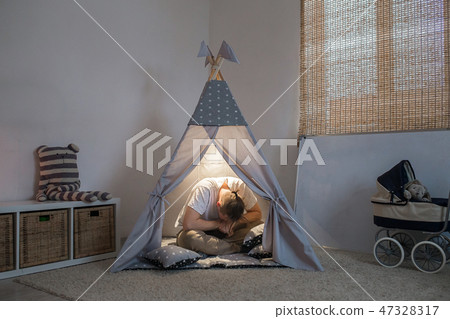 father frustrated and in despair sitting in the playroom 47328317