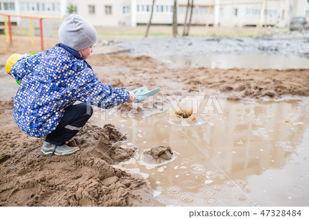 Boy playing in a muddy puddle 47328484