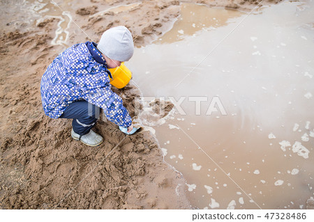 Boy playing in a muddy puddle 47328486