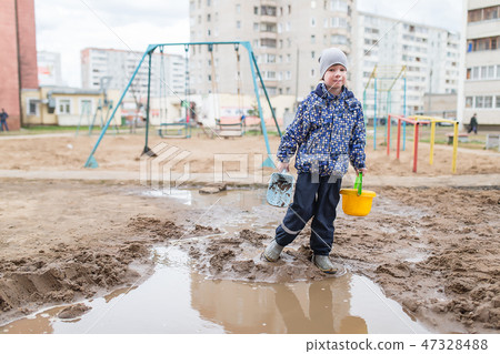 Boy playing in a muddy puddle 47328488