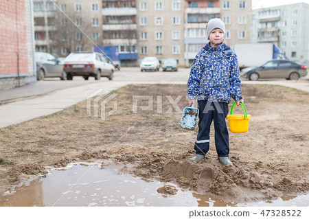 Boy playing in a muddy puddle 47328522