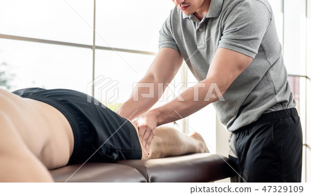 Male therapist giving leg massage to patient  47329109