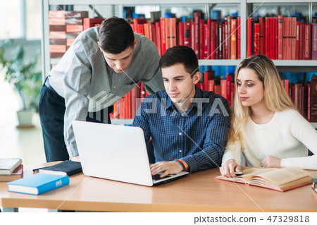 University students sitting together at table with books and laptop. Happy young people doing group 47329818