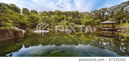 Mejiro Garden的Ikeizumi六角形的浮動大廳，反映了巨大的石頭，松樹，紅色的鳥和蘭花，以及在鯉魚周圍散佈的池塘周圍的水。 47330202