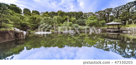 Mejiro Garden的Ikeizumi一個巨大的石頭在池塘里的鯉魚池塘周圍蔓延，一棵松樹，一個紅色的鳥屋和一個反射在水面上的六角形浮點 47330203