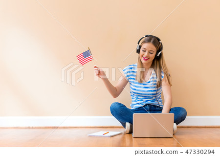 Young woman with USA flag using a laptop computer Young woman with USA flag using a laptop computer 47330294