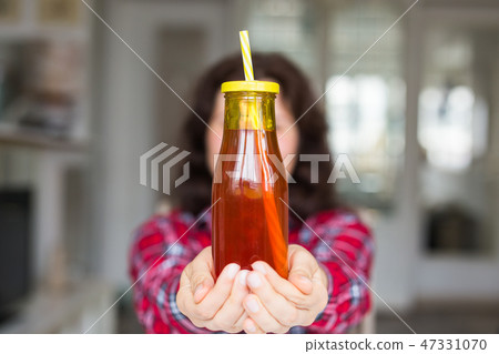 Drinks, diet and healthy lifestyle concept - woman giving you a bottle of natural juice Drinks, diet and healthy lifestyle concept - woman giving you a bottle of natural juice 47331070
