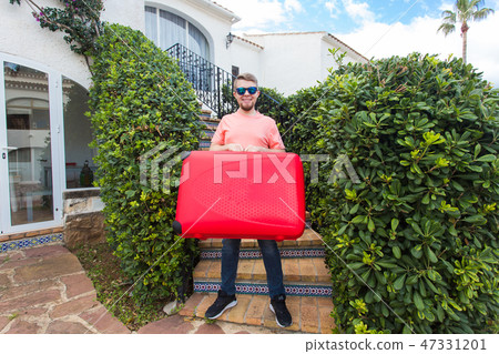 Travel, tourism and people concept - a young man standing on stair with red suitcase in his hand and Travel, tourism and people concept - a young man standing on stair with red suitcase in his hand and 47331201