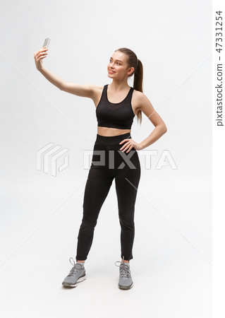 sporty woman making selfie photo on smartphone isolated on a white background. sporty woman making selfie photo on smartphone isolated on a white background. 47331254