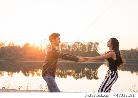 Romantic, social dance and people concept - young couple dancing bachata on the background of sunset Romantic, social dance and people concept - young couple dancing bachata on the background of sunset 47332191
