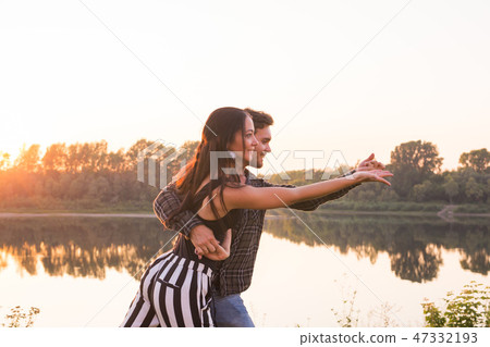 Romantic, social dance and people concept - young couple dancing a tango or bachata near the lake Romantic, social dance and people concept - young couple dancing a tango or bachata near the lake 47332193