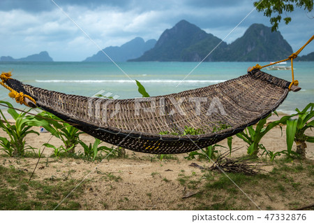 Traditional braided hammock in the shade with tropical island in the background 47332876