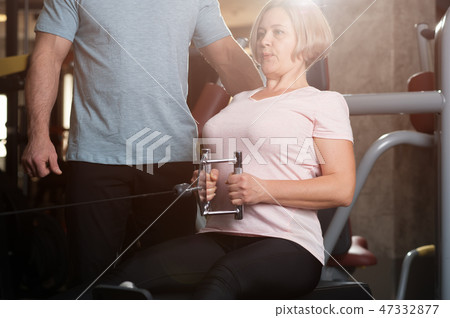 Personal trainer man helps an elderly woman 47332877