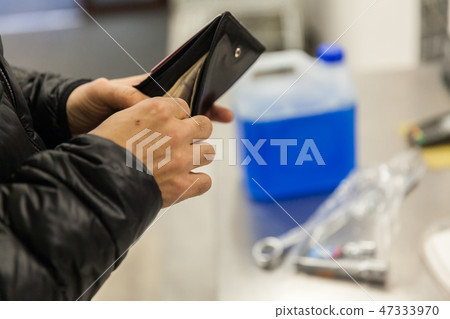man buys the antifreeze liquid into his car in the shop 47333970