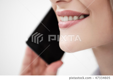Close-up of the mouth and lips of a woman talking on a smartphone on a white background. Close-up of the mouth and lips of a woman talking on a smartphone on a white background. 47334605