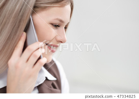 Close-up of the face and lips of a girl talking on a smartphone. Smile and friendly look. 47334825