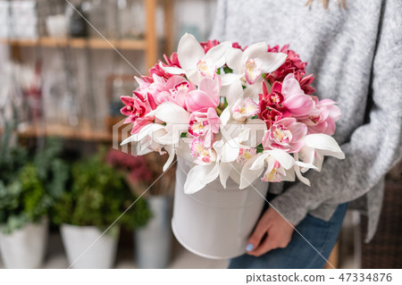 Japanese Wanda Orchid in metal vases in womens hands. Bunch pale pink. white. the concept of a Japanese Wanda Orchid in metal vases in womens hands. Bunch pale pink. white. the concept of a 47334876