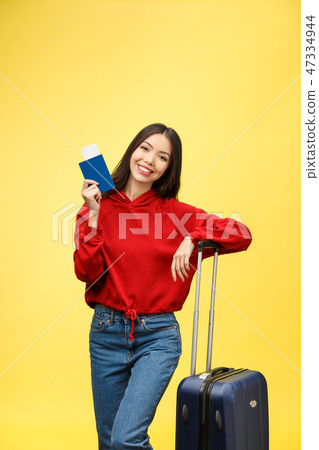 Woman travel. Young beautiful asian woman traveler with suitcase and passport on yellow background Woman travel. Young beautiful asian woman traveler with suitcase and passport on yellow background 47334944