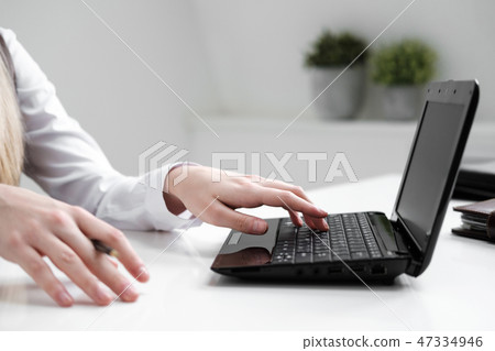 Close-up, girl's hands on the background of the white table, typing on a laptop. Close-up, girl's hands on the background of the white table, typing on a laptop. 47334946