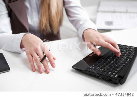 Close-up, girl's hands on the background of the white table, typing on a laptop. Close-up, girl's hands on the background of the white table, typing on a laptop. 47334948
