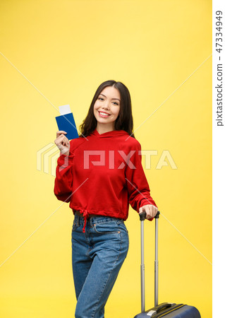 Woman travel. Young beautiful asian woman traveler with suitcase and passport on yellow background Woman travel. Young beautiful asian woman traveler with suitcase and passport on yellow background 47334949