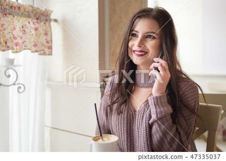 Happy young women speaks by phone in cozy cafe 47335037