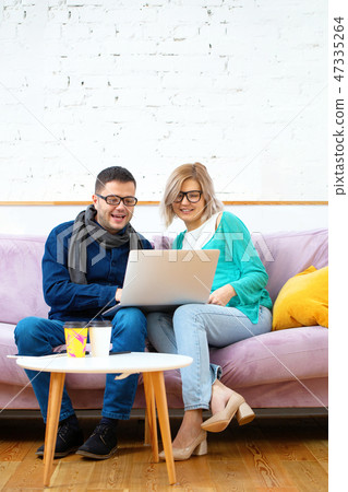 Friends sit on the couch, chatting and using a smartphone, desktop computer, laptop. Friends sit on the couch, chatting and using a smartphone, desktop computer, laptop. 47335264