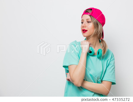 girl in pink cap and blue t-shirt with headphones girl in pink cap and blue t-shirt with headphones 47335272