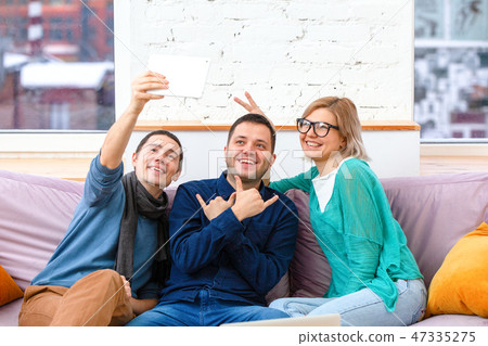 Friends sit on the couch, chatting and using a smartphone, desktop computer, laptop. Friends sit on the couch, chatting and using a smartphone, desktop computer, laptop. 47335275