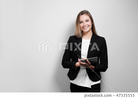 Portrait of a beautiful smiling woman blonde with a tablet in her hands in a business suit and Portrait of a beautiful smiling woman blonde with a tablet in her hands in a business suit and 47335555