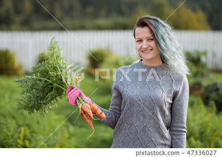 A girl with colored hair, a farmer holding a fresh carrot. A girl with colored hair, a farmer holding a fresh carrot. 47336027