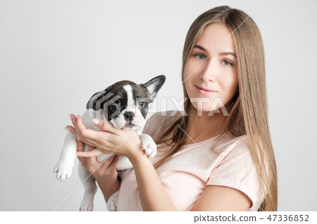 A beautiful young girl is holding a puppy of a French bulldog. A beautiful young girl is holding a puppy of a French bulldog. 47336852