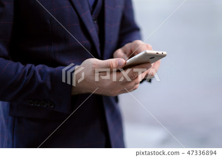 Phone in the hands of a businessman businessman in a business suit. Phone in the hands of a businessman businessman in a business suit. 47336894