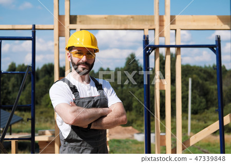 The man is a builder on the roof of a wooden frame house. The man is a builder on the roof of a wooden frame house. 47339848