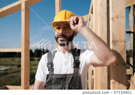 The man is a builder on the roof of a wooden frame house. The man is a builder on the roof of a wooden frame house. 47339901