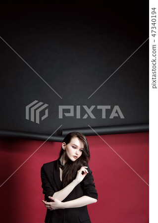Portrait of a beautiful model girl in a business suit on a ragged red and black background. Hands Portrait of a beautiful model girl in a business suit on a ragged red and black background. Hands 47340194