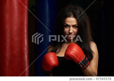 Serious young woman with boxing gloves Serious young woman with boxing gloves 47343578