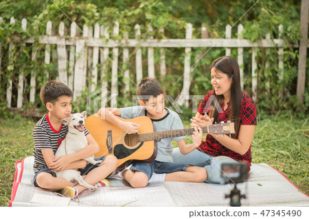 Single mom and son play guitartogether with fun in the park Single mom and son play guitartogether with fun in the park 47345490