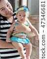 asian woman holding baby cute swimming suite in her arms 47346681