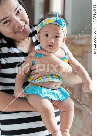 asian woman holding baby cute swimming suite in her arms asian woman holding baby cute swimming suite in her arms 47346681